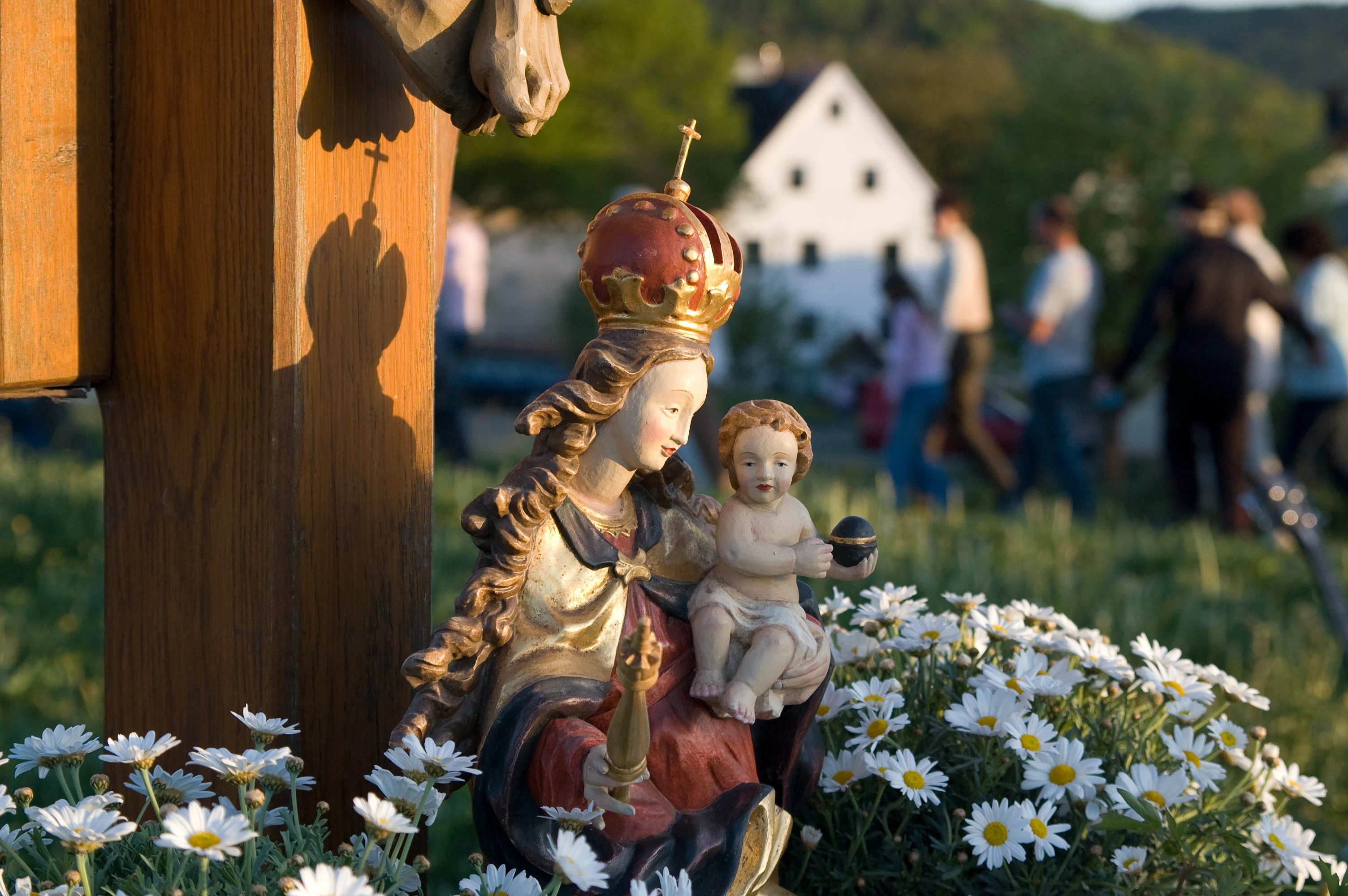 Marienfigur mit Kerzenlicht und Blumenschmuck